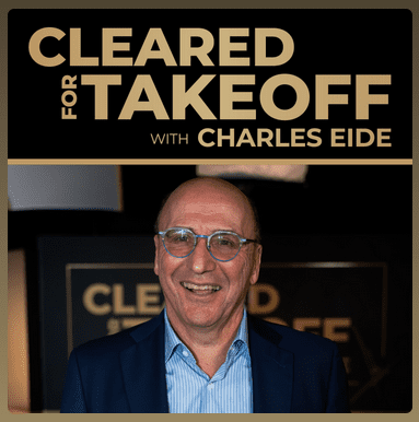 Resilient-Now: A man wearing glasses and a suit smiles in front of a sign that reads "Cleared for Takeoff with Charles Eide.